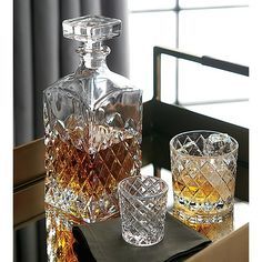 two glasses and a decanter sitting on a table in front of a window