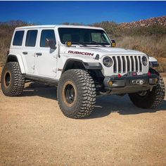 a white jeep parked on top of a dirt field