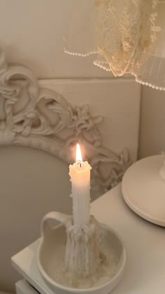 a lit candle sitting on top of a white plate