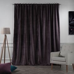 a living room with a couch, chair and window covered in dark purple drapes