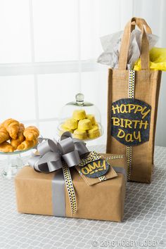 a birthday present sitting on top of a table next to a brown bag filled with treats