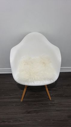 a white chair sitting on top of a hard wood floor next to a gray wall