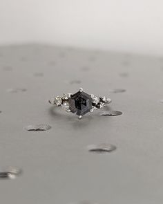 a black diamond ring sitting on top of a silver surface with drops of water around it