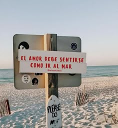 a sign that is on the side of a wooden pole in front of the beach