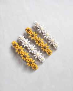 four small yellow and white flowers sitting on top of a white table next to each other