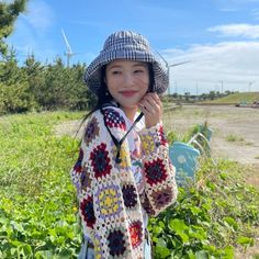 a woman wearing a hat and holding a cell phone up to her ear while standing in a field