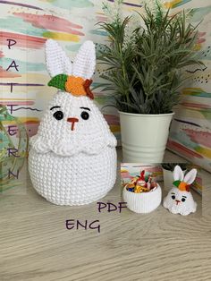 a white crocheted easter bunny sitting next to a potted plant on a table