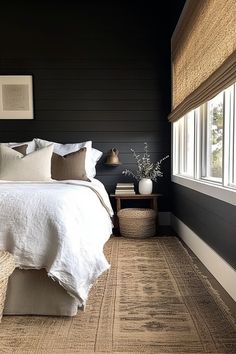 a bedroom with black walls, white bedding and tan carpeted area rugs