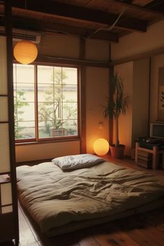 a bed sitting in a bedroom under a window next to a wooden floor and lamp