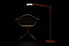 a chair with a light on it next to a floor lamp in the dark room