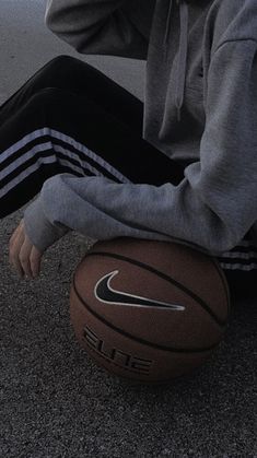 a person sitting on the ground with a basketball in front of their feet and head