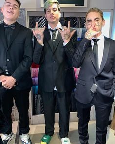 three men in suits and ties posing for the camera with their hands up to their mouths