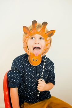 a young boy wearing a giraffe mask and holding a toothbrush in his mouth