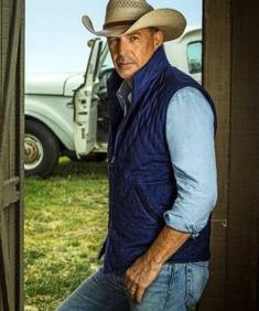 a man wearing a cowboy hat standing in front of a truck