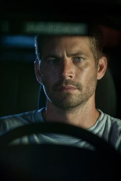 black and white photograph of a man in a car looking at the camera with an intense look on his face