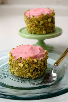 two cupcakes with pink frosting and sprinkles are on a glass plate