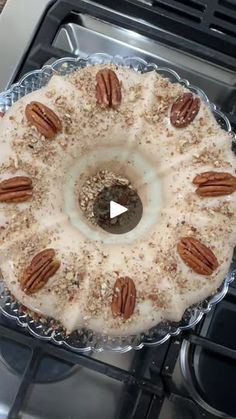 a cake sitting on top of a stove covered in frosting and pecans