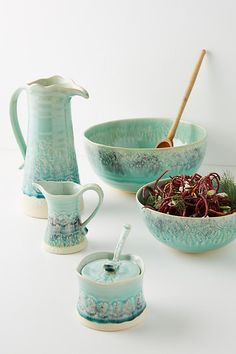 three bowls and one pitcher are sitting next to each other on a white table top