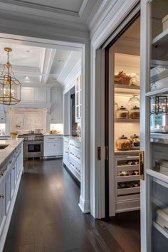 an open door leading into a kitchen with white cabinets and wood flooring on both sides