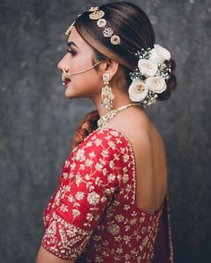 a woman in a red and gold dress with flowers in her hair, looking off to the side