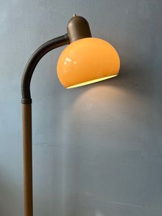 an orange lamp on a gray wall next to a brown pole with a yellow light