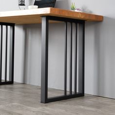 a wooden table sitting on top of a hard wood floor next to a white wall