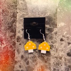 a pair of yellow and white earrings sitting on top of a marble counter next to a black box