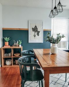 a dining room table with two chairs and a potted plant on the far wall