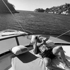 a man laying on the back of a boat while talking on a cell phone in front of him