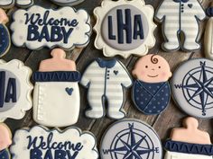 baby shower cookies decorated with blue and white icing on a wooden surface, including the words welcome baby