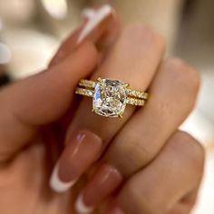 a woman's hand holding an engagement ring with a yellow and white diamond in it