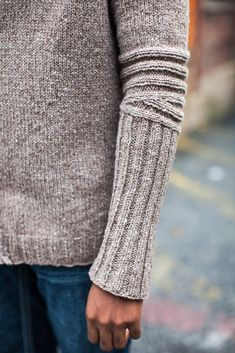 a close up of a person's hand holding something in their other hand and wearing a sweater