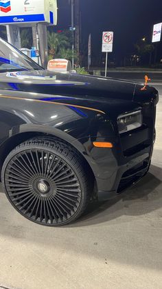 a black sports car parked in front of a gas station with its hood up and wheels down