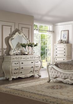 a bedroom with white furniture and an ornate mirror on the dresser, bed, and window