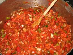 a pot filled with lots of red food and a wooden spoon in the middle of it