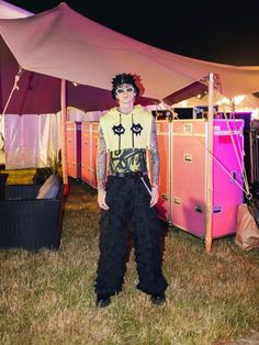 a man standing in front of a tent with his hands on his hips and wearing sunglasses