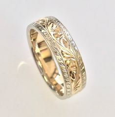 a gold wedding ring with filigrees and leaves on the inside, set against a white background