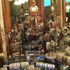 an assortment of bracelets and necklaces on display in a store window with a clock