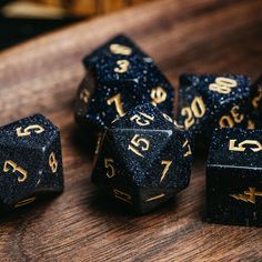 black and gold glittered dice sitting on top of a wooden table next to each other