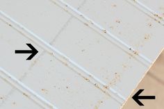 two arrows pointing to the left side of a white painted wall with vertical lines on it