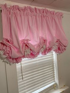 a pink and white checkered window valance with ruffles hanging from it