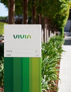 a green and white sign sitting on the side of a road next to some trees