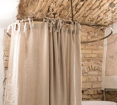 a white toilet sitting next to a shower curtain in a bathroom under a wooden roof