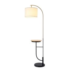 a floor lamp with a white shade on the top and a wooden table underneath it