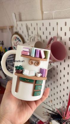 a person holding a coffee mug with some type of crafting supplies on top of it