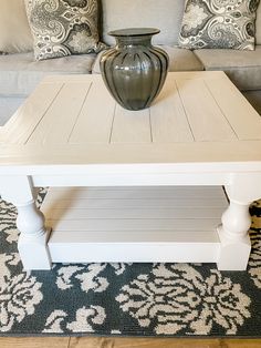 a white coffee table with a vase on top