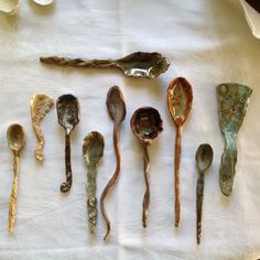 seven spoons are lined up on a white cloth