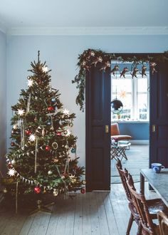 a decorated christmas tree sitting in the middle of a living room next to a doorway