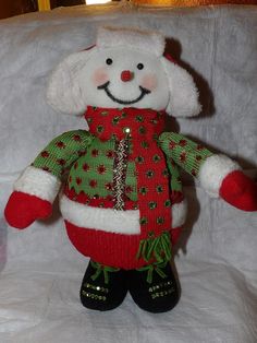 a white stuffed animal wearing a red and green sweater