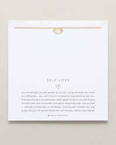 a white card with a gold chain attached to it that says self love on the front